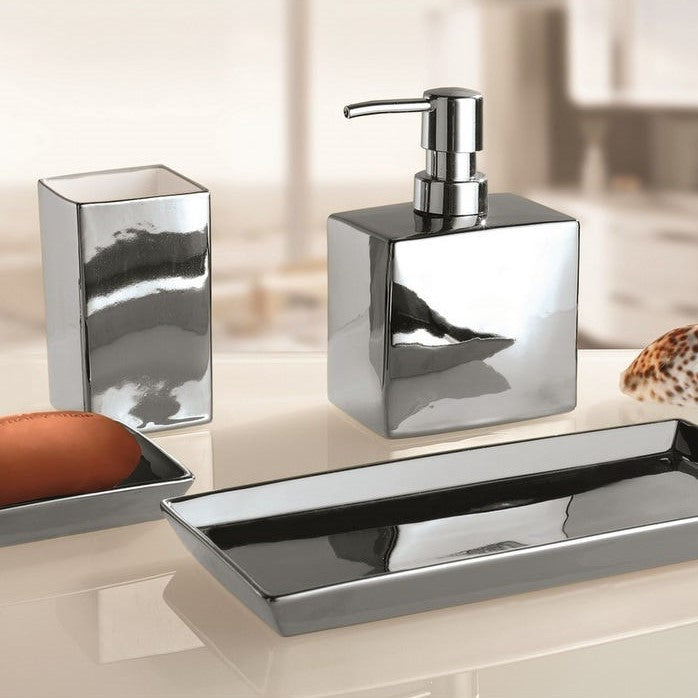 Three-piece chrome bathroom accessory set including a soap dispenser, tooth holder, and tray, displayed on a light beige countertop with a blurred bathroom background.