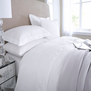 A white duvet cover on a bed, with a sateen finish and envelope style opening.
