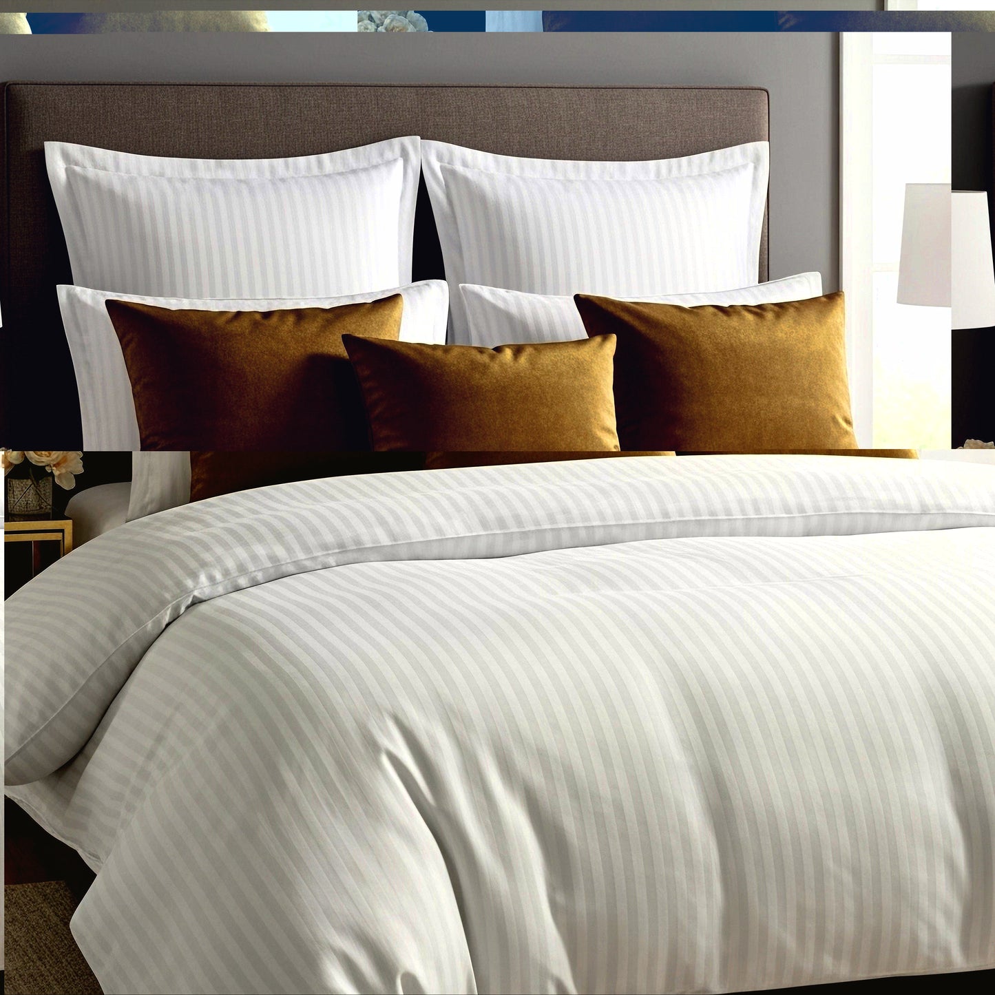 Neatly made bed with Egyptian cotton
satin striped bedding and decorative pillows in a bedroom setting.