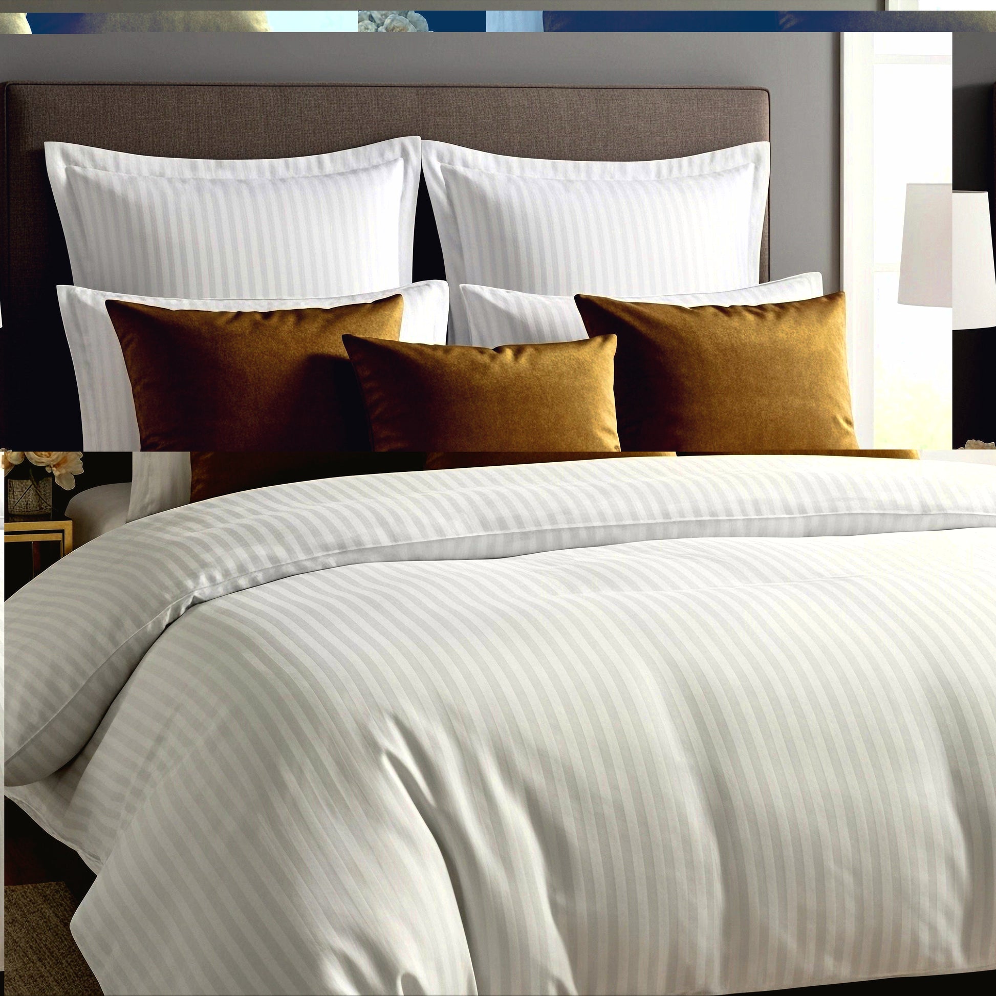 Neatly made bed with Egyptian cotton
satin striped bedding and decorative pillows in a bedroom setting.