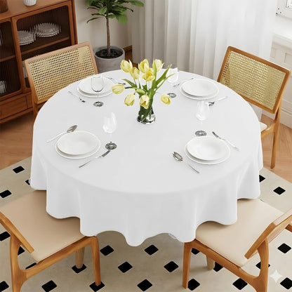 Dining table set with white tablecloth, plates, and yellow flowers in a room with wooden chairs and a black and white checkered floor.
