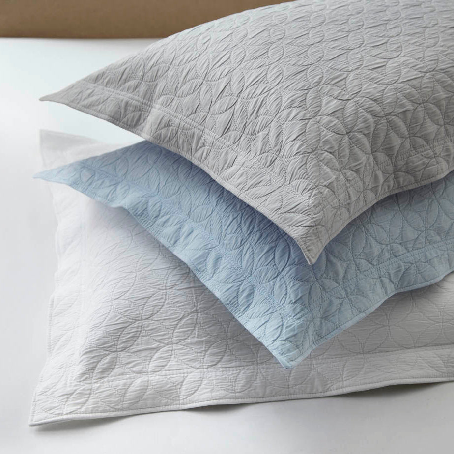 Quilted gray and white bedding set on a bed