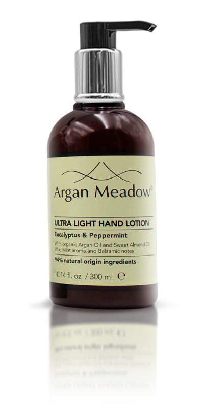 A pump bottle of Argan Meadow hair wash placed on a rocky surface with a body of water in the background.