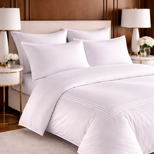 White bedding set on a bed in a bedroom with wooden headboard and lamps.
