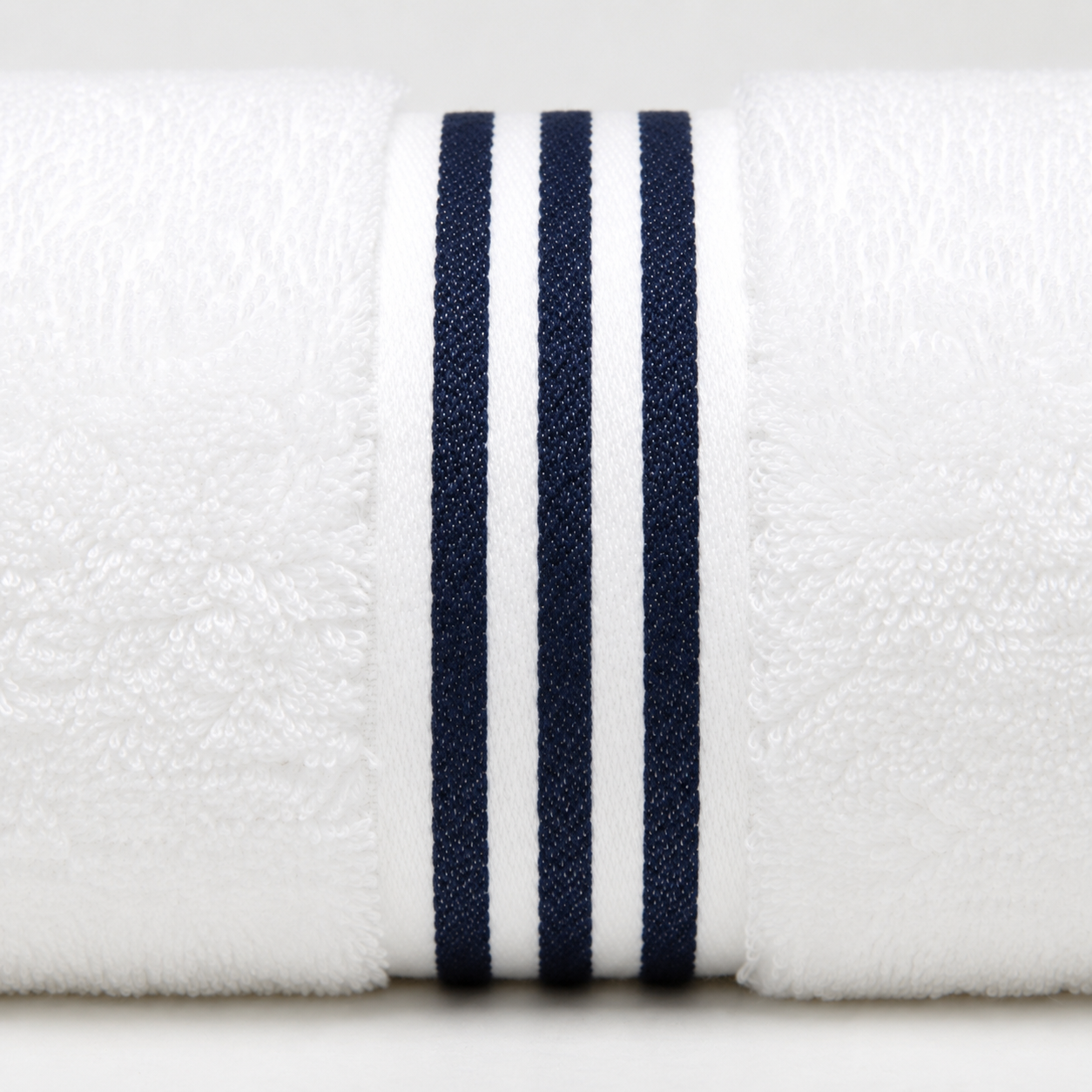 A close-up of a white textured towel roll featuring three vertical navy blue stripes on the front edge.