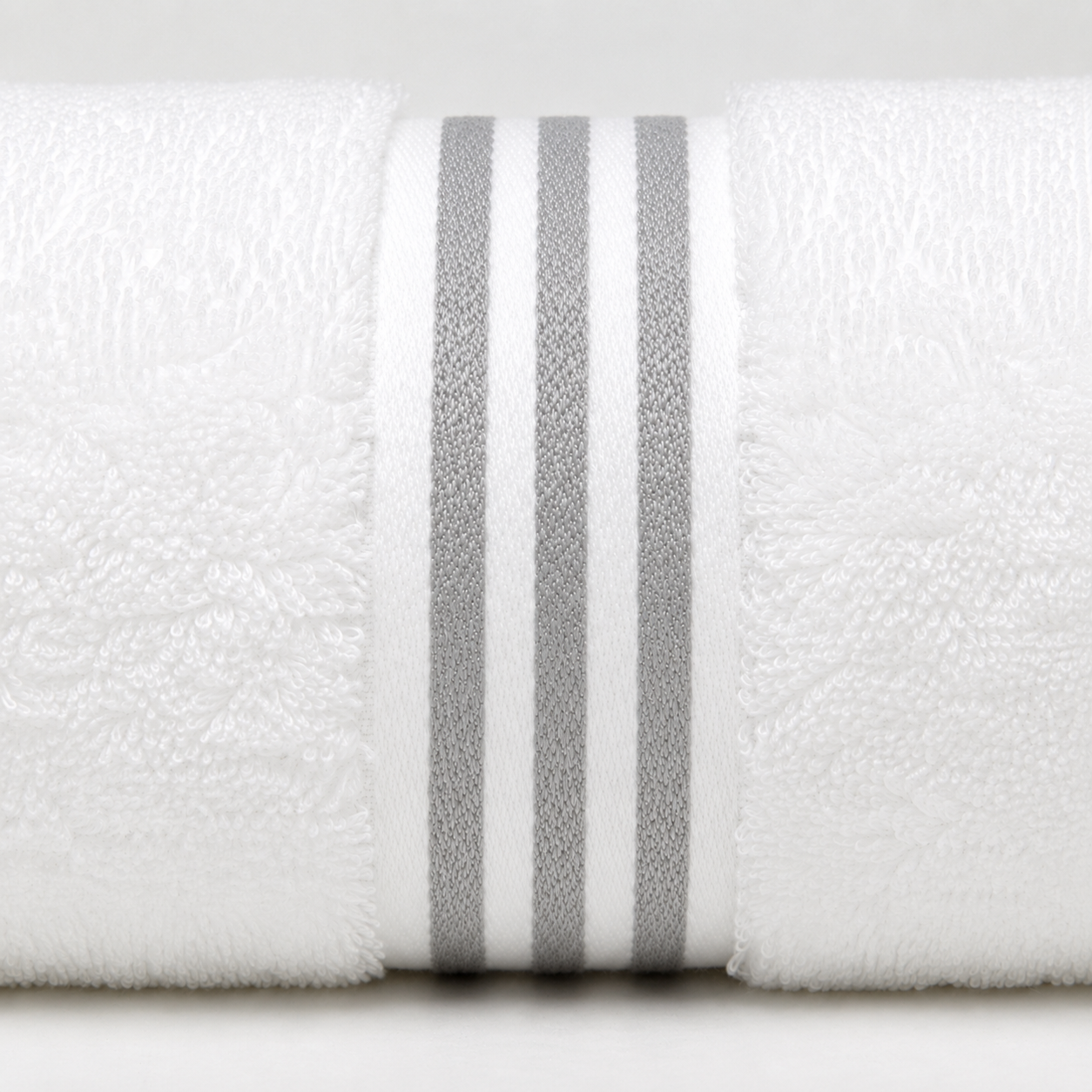 A close-up of a white textured towel rolled up, featuring three vertical gray stripes around the center.