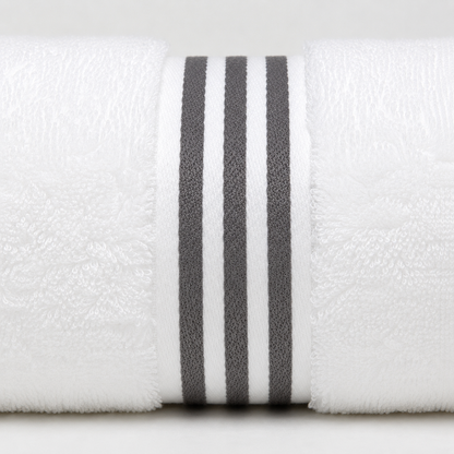 A close-up of a white textured towel roll with three vertical dark gray stripes near the center, photographed against a light neutral background.