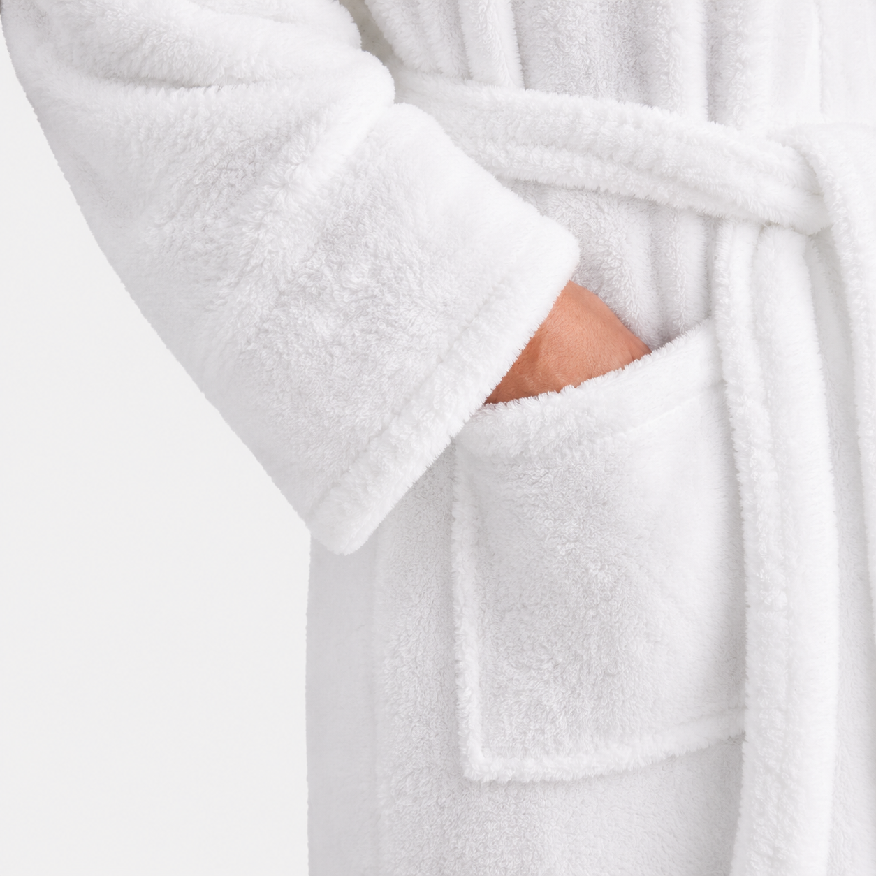 Close-up of a plush white bathrobe with a matching tie belt and front patch pocket, shown on a person whose hand is tucked into the pocket.