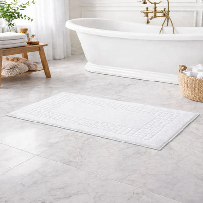 Bathroom with a white bath mat, freestanding bathtub, and basket of towels.