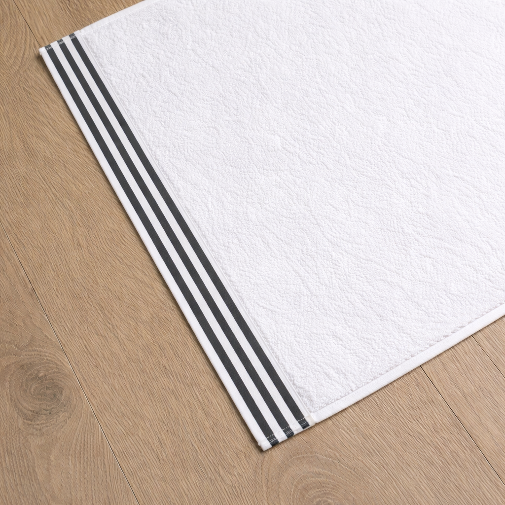 White towel with dark grey stripes on a wooden floor
