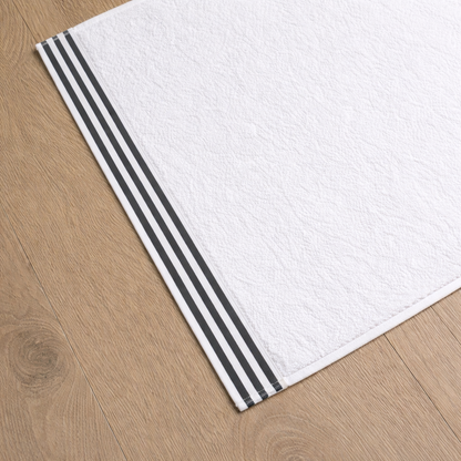 White towel with dark grey stripes on a wooden floor