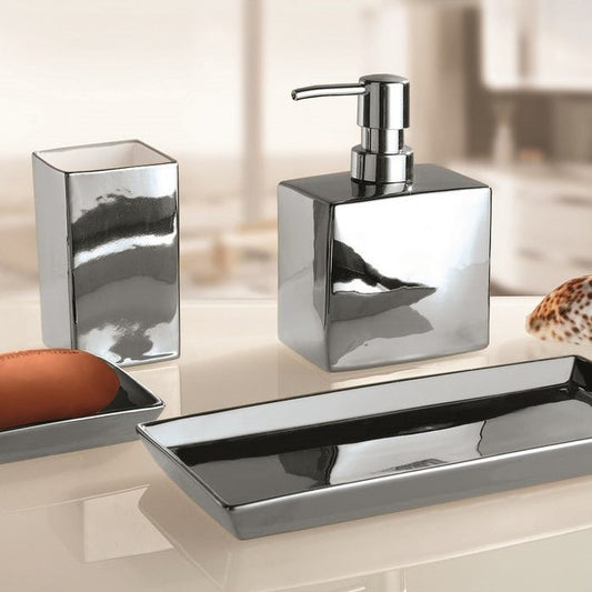 Three-piece chrome bathroom accessory set including a soap dispenser, tooth holder, and tray, displayed on a light beige countertop with a blurred bathroom background.