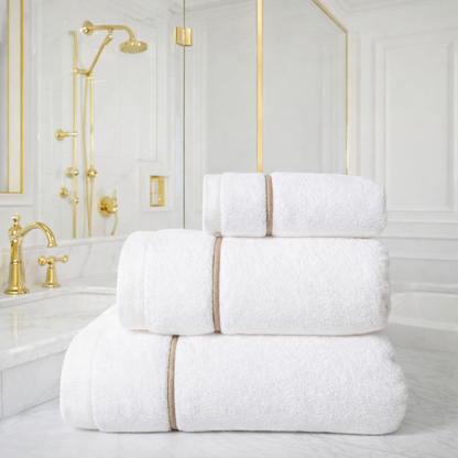 Stack of white towels with gold trim in a bathroom setting